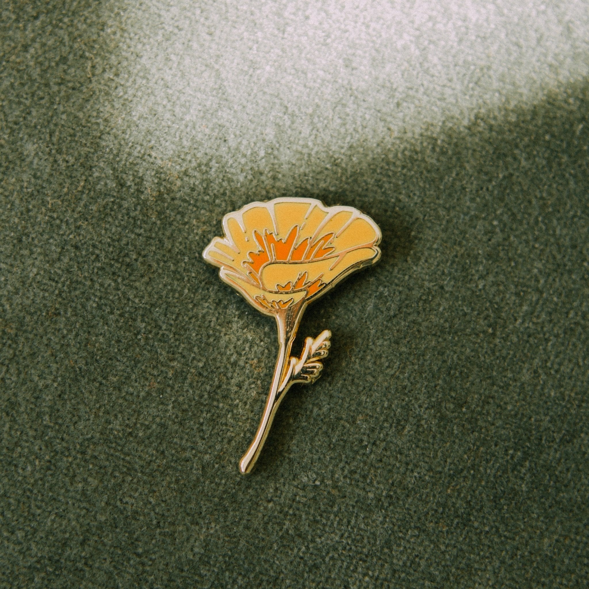a hard enamel pin of an orange california poppy wildflower made from hard enamel and gold metal plating. a cute plant wildflower pin for backpacks, totes, hats, lapels, and jackets