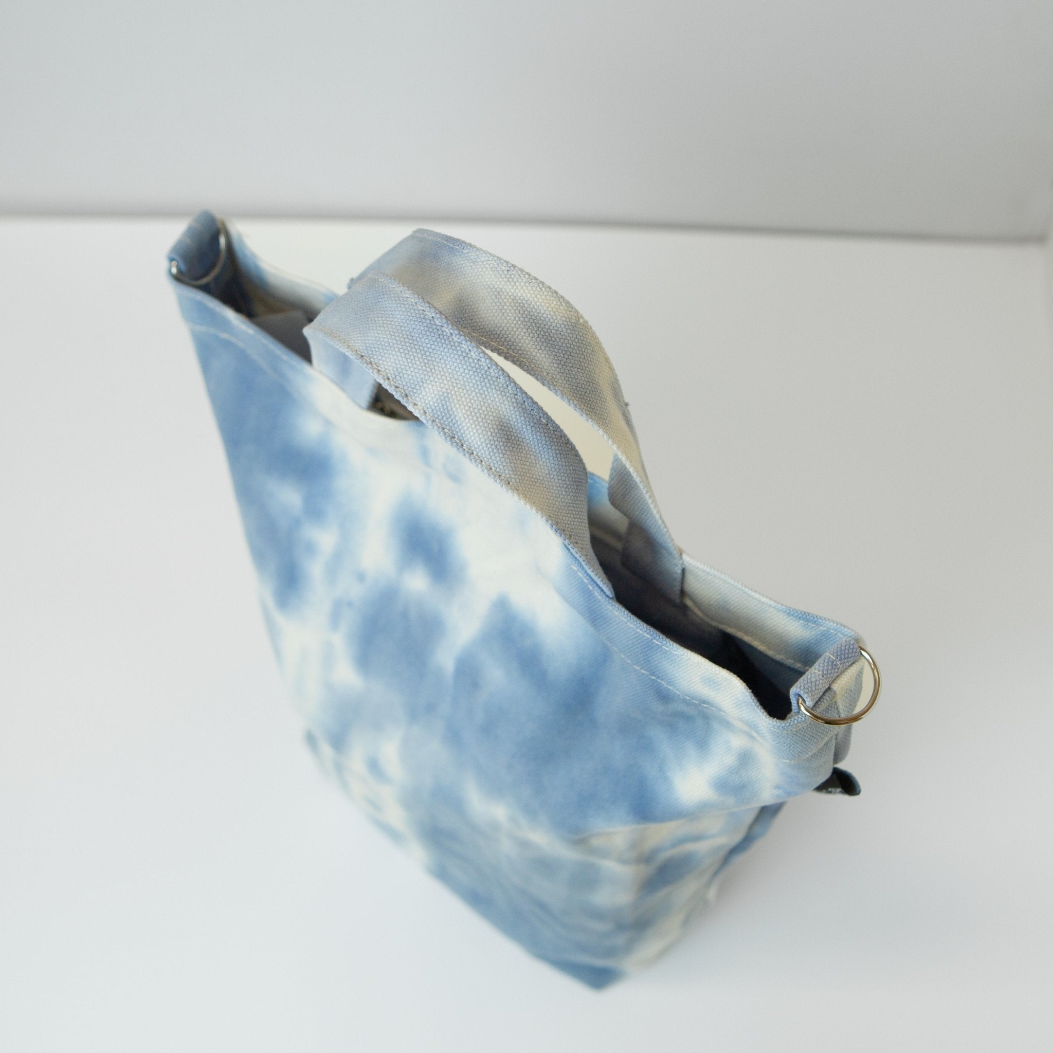 a tie dyed canvas tote in a pale blue and white color 