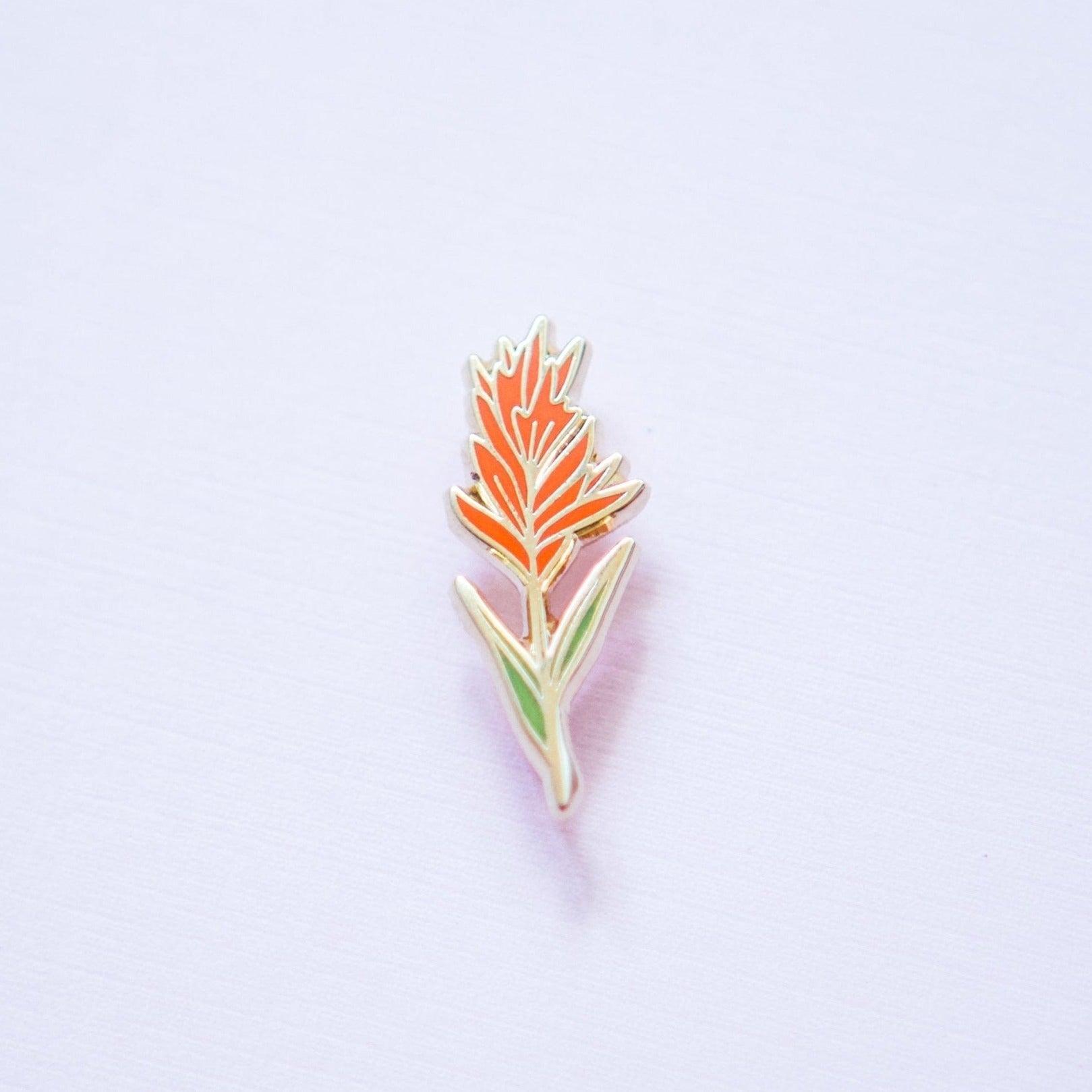 an indian paintbrush plant wildflower enamel pin made from red and green hard enamel and gold metal plating
