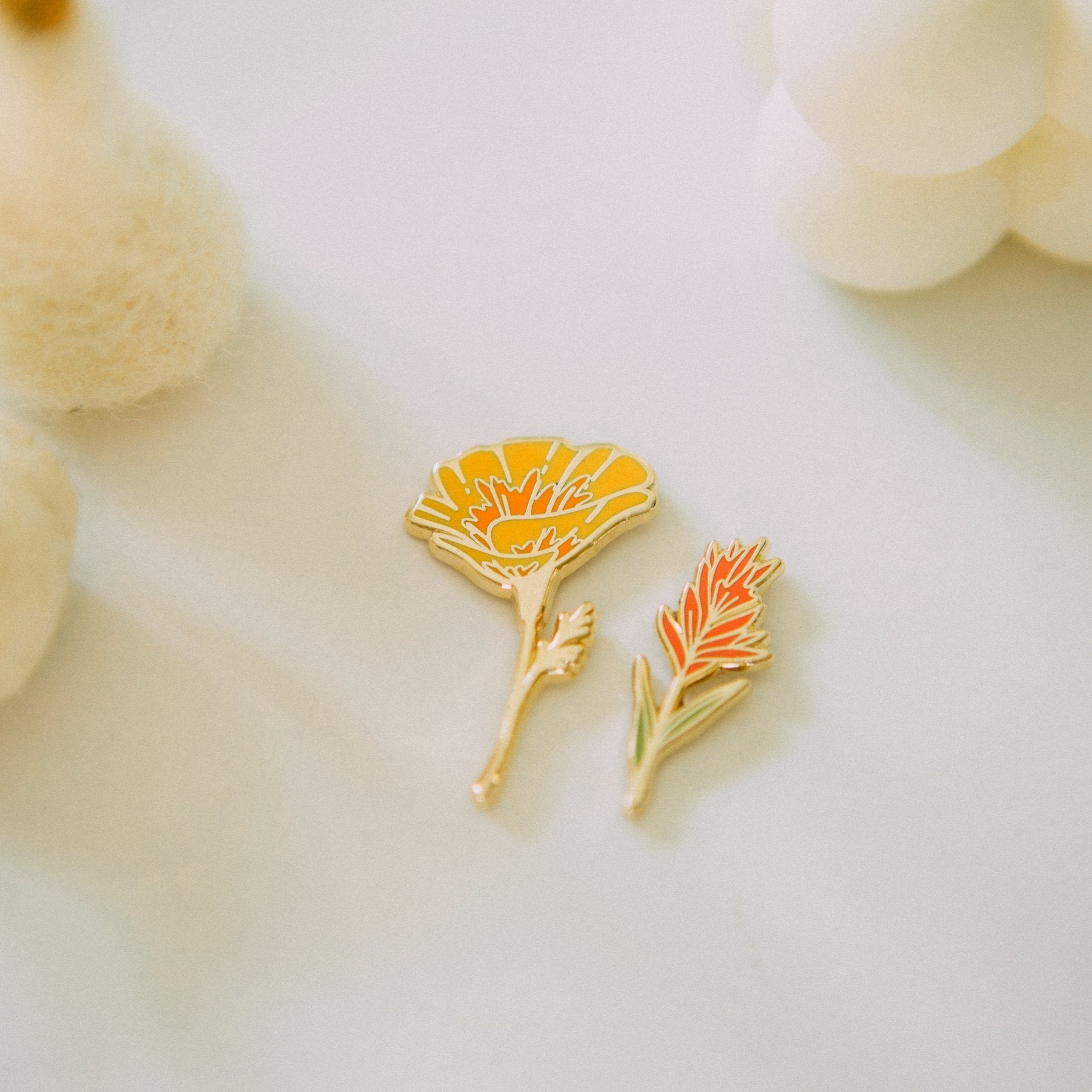 a hard enamel pin of an orange california poppy wildflower made from hard enamel and gold metal plating. a cute plant wildflower pin for backpacks, totes, hats, lapels, and jackets