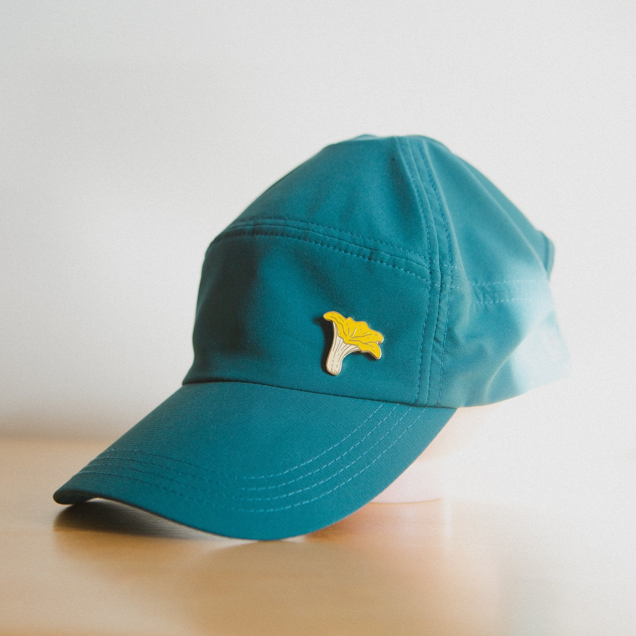 a hard enamel pin of an orange chanterelle mushroom on a hat