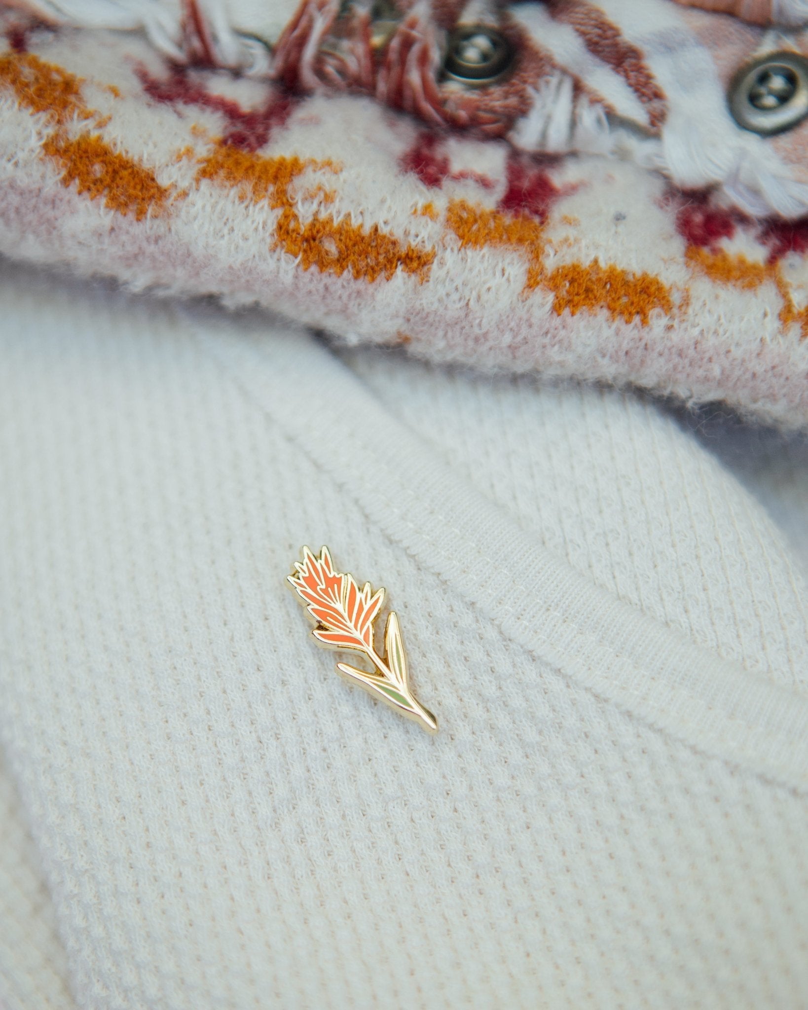 an indian paintbrush plant wildflower enamel pin made from red and green hard enamel and gold metal plating